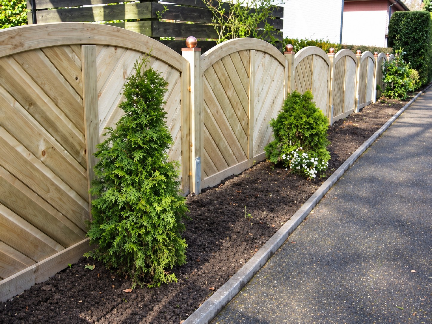 Neu errichteter heller Holzzaun entlang eines Gartenwegs